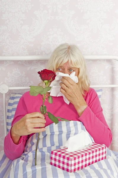 Sick woman in bed with roses and tissues — Stock Photo, Image