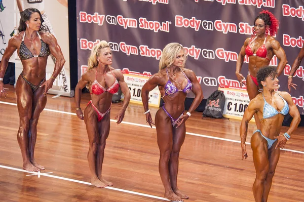 Female bodybuilders show their side chest post on stage — Stock fotografie