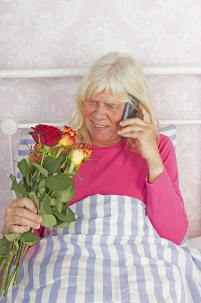 Mujer en la cama con rosas y teléfono — Foto de Stock