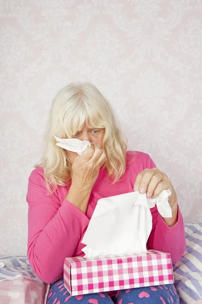 Woman on bed blowing nose — Stock Photo, Image