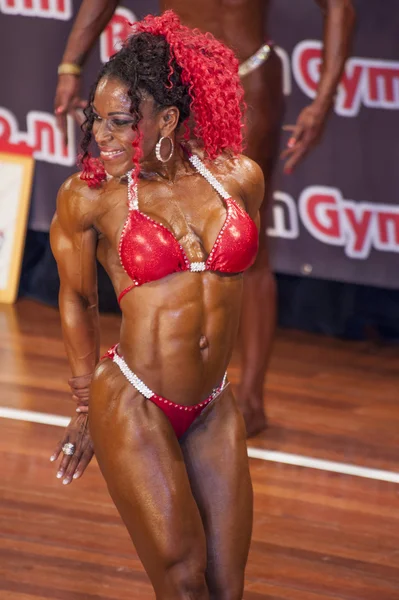 Female bodybuilder in triceps pose and red bikini — Stock fotografie