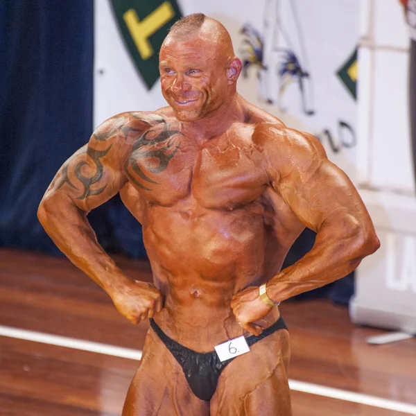 Male bodybuilder shows his best lats spread pose on stage — Stock Photo, Image