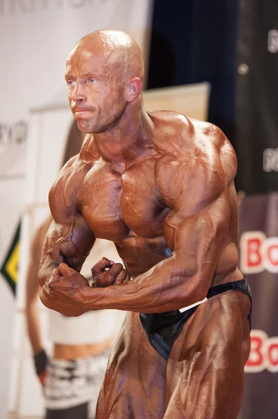 Male bodybuilder shows his best most muscular pose on stage — Stock Photo, Image