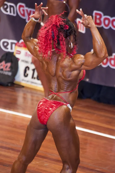 Feminino fisiculturista nas costas duplo bíceps pose e biquíni vermelho — Fotografia de Stock