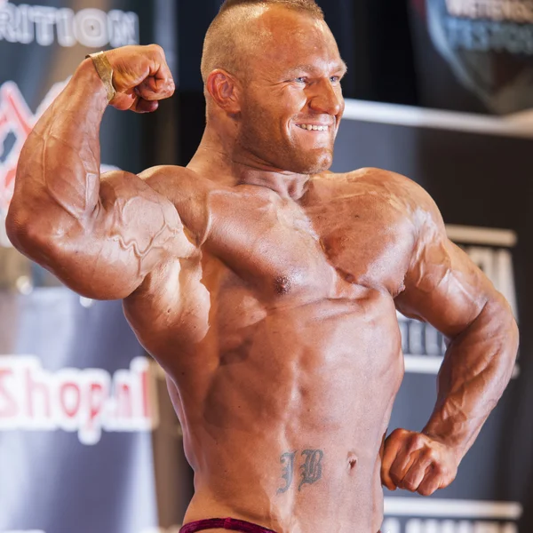 Male bodybuilder shows his big biceps on stage — Stockfoto