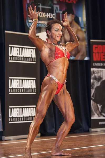 Female bodybuilder in double biceps pose and red bikini — Stock fotografie