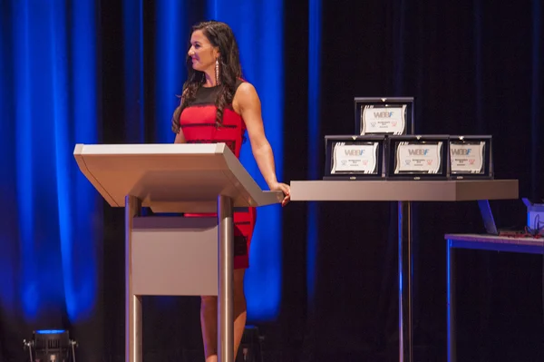 Master of ceremonies behind pulpit addresses theatre crowd with — Stock Photo, Image