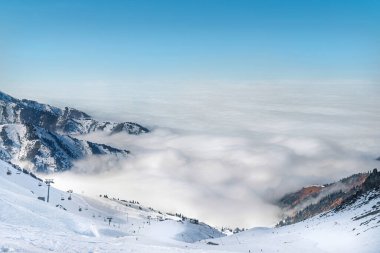 Bulutlu Tian Shan dağlarındaki kayak merkezi Almaty şehrinin yakınlarında sisli bir tepede..