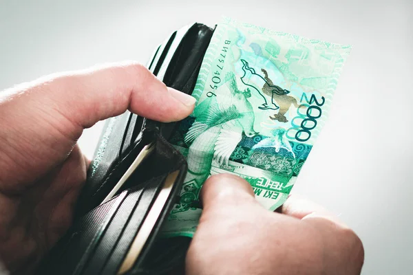 Siyah cüzdanı tenge ile aç, Kazakistan parası adamın elinde.