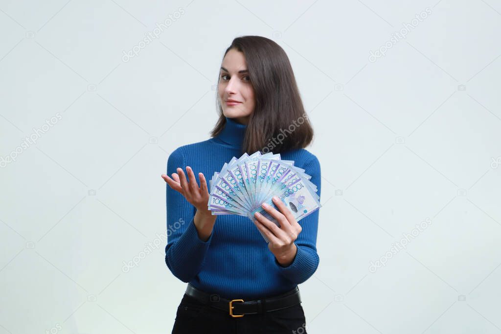 Image of a young woman with big tenge money on a white background