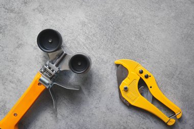 PVC borular ve boru kesme makası için sarı lehimleme demiri, gri arkaplan üzerinde su tedarik araçları.