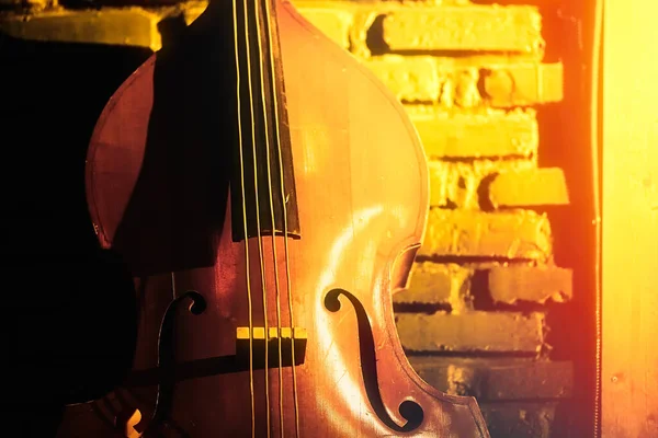 Крупним планом подвійний бас на цегляному фоні стіни в клубному підвалі, підземна джазова музика . — стокове фото