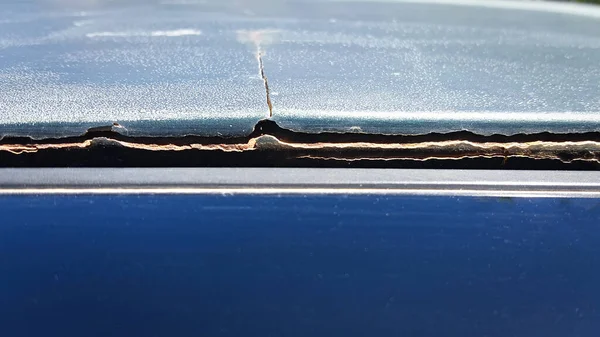 Poor-quality car body repair. The putty is peeling off the metal. Large cracks on the roof of the vehicle