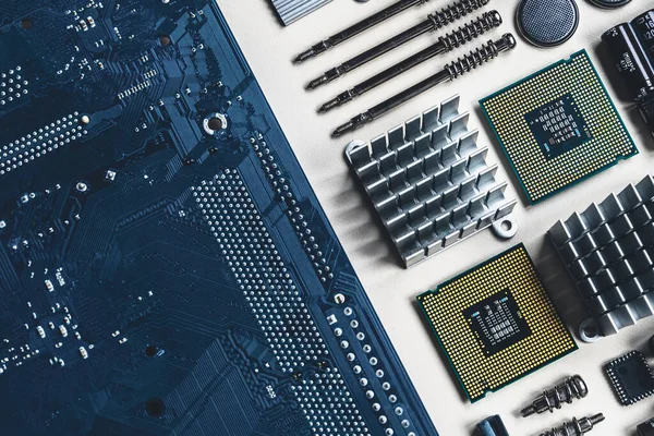 Top view of computer parts with CPU, battery, capacitors, chip, screwdrivers on white table background with copy space