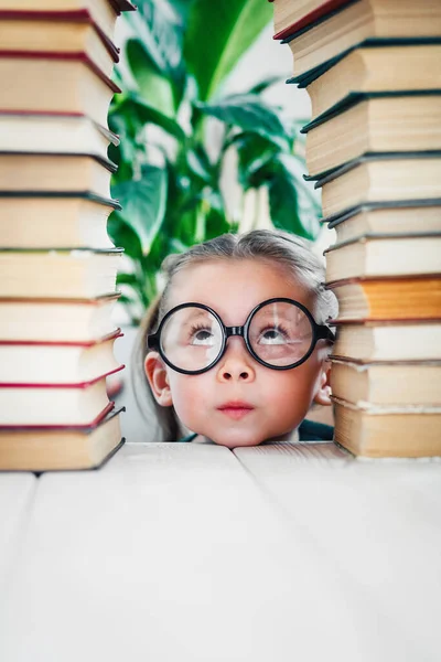 Kids development and education concept. Little girl in glasses between two books towers with copy space — Stock Photo, Image