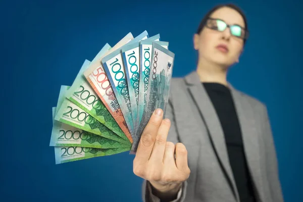 Gri ceketli bir kadının elinde, Kazakistan 'ın çeşitli banknotlarının yakın çekim görüntüleri var. Seçici odak