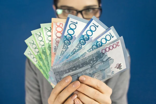 Mujer mirando a la cámara sobre Kazajstán tenge dinero en sus manos —  Fotos de Stock