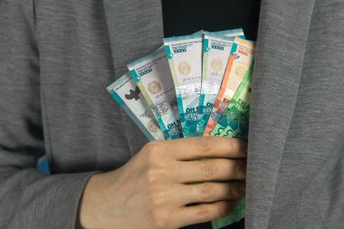 Kadın, gri ceketin iç cebinden tenge çıkardı.