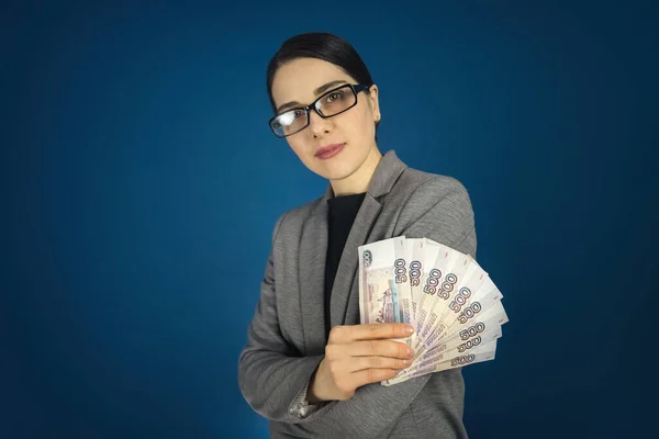 Gözlüklü güzel genç bir kadın elinde bir sürü Rus rublesi tutuyor. — Stok fotoğraf