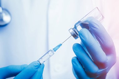 Şırınga ve ampul kullanarak doktor kolunu kapat. Beyaz bornoz giymiş, geçmişi bulanık. Tıbbi, aşılama ve aşılama kavramı
