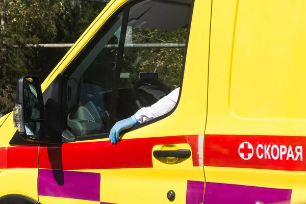 A mão de um motorista de ambulância na proteção contra vírus e uma luva está na janela de um carro de ambulância — Fotografia de Stock