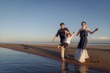 Çocuklu genç bir aile sahilde eğleniyor. Boşluğu kopyala