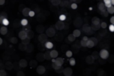 Harmanlama kipi için siyah arkaplan üzerinde yumuşak beyaz bokeh daireler.