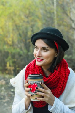 Beautiful woman in a black hat holds a cozy cup in her hands. Bright smile and good mood. clipart