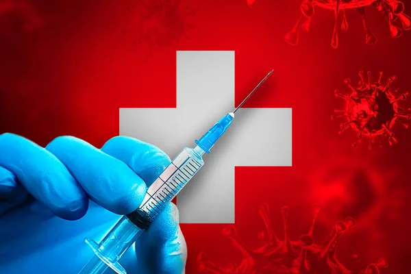 Switzerland Covid-19 Vaccination Campaign. A hand in a blue rubber glove holds a syringe with covid-19 virus vaccine in front of Switzerland flag. Coronavirus vaccination concept