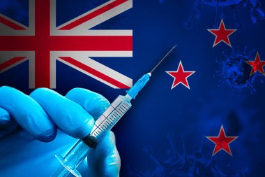 Yeni Zelanda Covid-19 Aşı Kampanyası. Mavi lastik eldivenli bir el, Yeni Zelanda bayrağı önünde üzerinde covid-19 virüsü aşısı bulunan bir şırınga taşıyor. Coronavirus aşısı konsepti