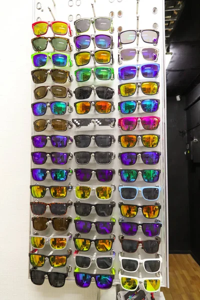 A stand of colorful various sunglasses, red, yellow, green and blue. Vertical — стокове фото