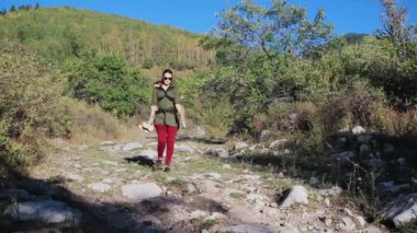 Bebek giyen bir kadın, bebeği askıda bir dağda yürür.