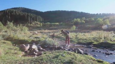 Anne kızıyla birlikte dağ nehrinden geçiyor.