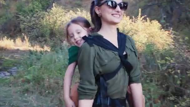 Новонароджена щаслива жінка йде по схилу гори зі своєю дитиною в слінгу — стокове відео