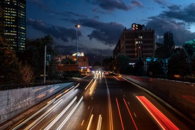 Şehir binaları ve dağlarla çevrili bir yolda gece trafiği yoğun. Almaty, Kazakistan - 3 Ekim 2024