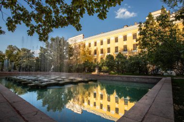 Bilim Akademisi 'nin büyük şehir çeşmesindeki altın saat yansıması. Almaty, Kazakistan - 3 Ekim 2024