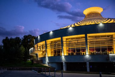 Devlet Sirki 'nin ikonik dairesel binası geceleri altın ışıklarla aydınlanıyor. Almaty, Kazakistan - 3 Ekim 2024