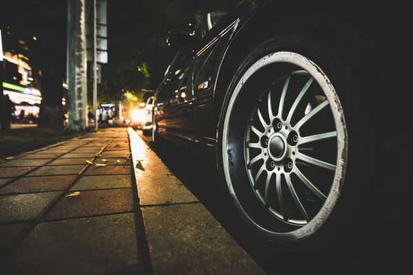 Gece vakti siyah bir arabanın arka planında gümüş renkli, çok dilli bir tekerlek kenarının detaylı çekimi. Almaty, Kazakistan - Ekim 04, 2024