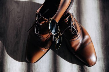 Lüks ve klasik kahverengi damat ayakkabıları ve pahalı gözlükler.