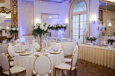 Düğün salonunun zarif ve pahalı dekoru - beyaz çiçekler, altın, masalar, şık avizeler