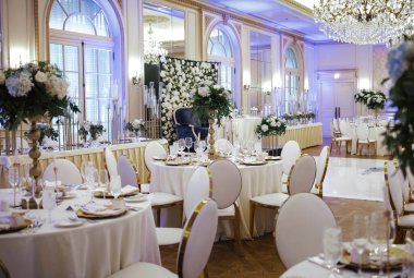 Düğün salonunun zarif ve pahalı dekoru - beyaz çiçekler, altın, masalar, şık avizeler