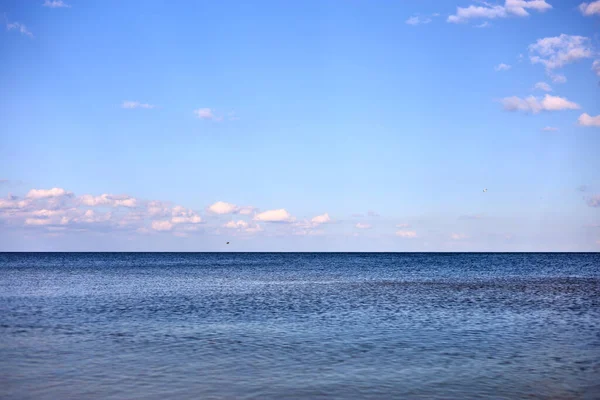 Bulutlu mavi gökyüzüne karşı sakin deniz suları