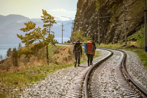 Groep vrienden wandelen met rugzakken in zonsondergang vanaf achterkant. — Stockfoto