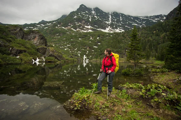 Chica con mochila disfrutando de la vista de un hermoso lago — Foto de Stock