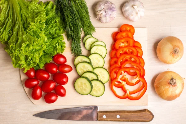 Verduras, tabla de cortar y cuchillo en una mesa — Foto de Stock