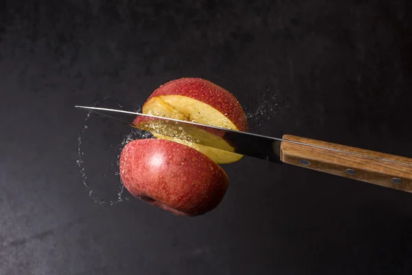 Knife and apple cut are frozen in mid air