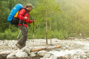 Bir ormandaki nehir boyunca yürüyen adam uzun yürüyüşe çıkan kimse