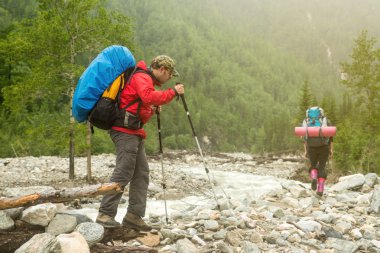 Bir ormandaki nehir boyunca yürüyen adam uzun yürüyüşe çıkan kimse