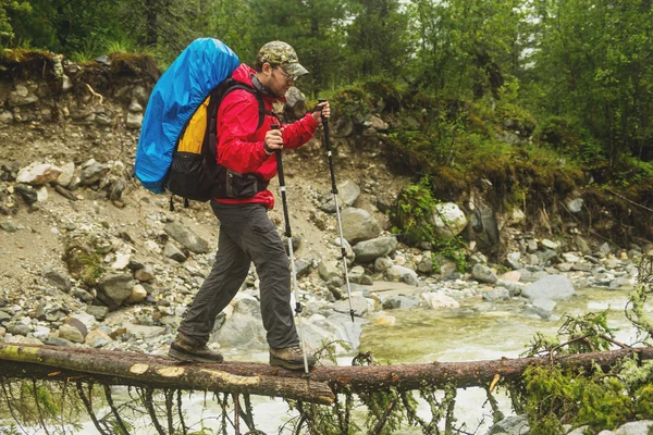 Человек-турист, идущий через реку в лесу — стоковое фото
