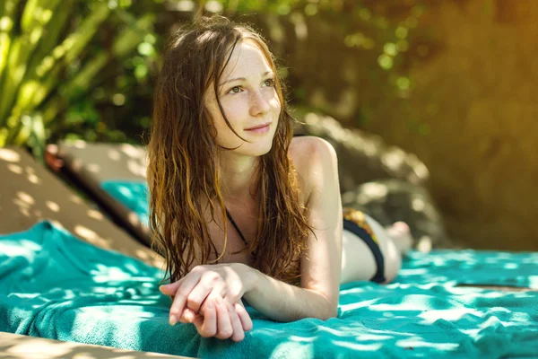 Flicka njuter solen leende som liggande på handduk tittar bort. — Stockfoto